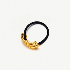 Detail of black elastic hair tie with curved gold metal accent on white background