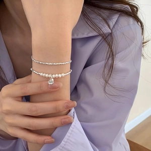 Detail of s925 silver double-layer bracelet with freshwater pearls and lily bell charm