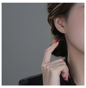 Detailed close-up of a silver s925 snake stud earring worn by a model in soft light