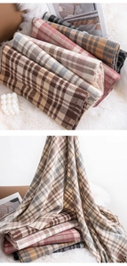 Stack of warm plaid scarves in multiple colors on a soft white faux fur rug