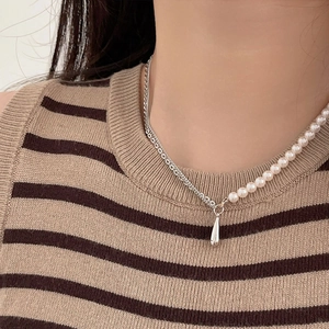 Detail of asymmetric 925 silver necklace with white pearls and a teardrop metal pendant