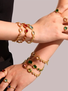 Detailed view of layered 18k gold plated bracelets and rings with colorful cubic zirconia
