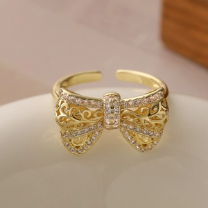 Elegant 18K gold-plated cutout bow open ring with pavé zircons on ceramic bowl
