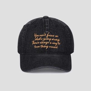 Gros plan de la broderie orange sur une casquette en jean noir délavé vintage