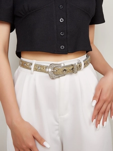 Close-up of gold rhinestone belt with western buckle on white trousers and black top