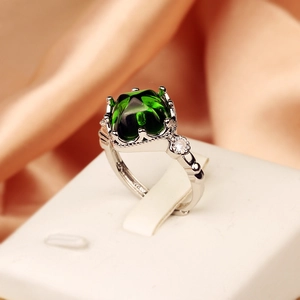Side view of silver ring with green sugarloaf stone and crown-shaped diamond details