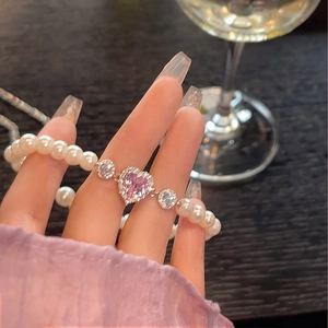 Gros plan d'un bracelet de perles blanches avec cristal en cœur rose sur le poignet