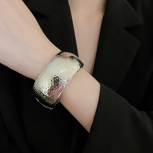 Detailed view of silver wide cuff bracelet with hammered texture on black background