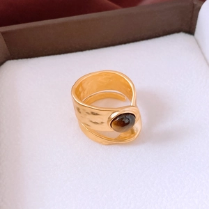 Macro view of gold hammered texture ring with round tiger eye stone in a jewelry box