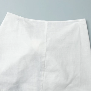 Detail of white linen blend dress showing natural fabric texture and flat seam stitching
