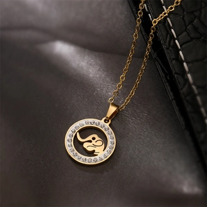 Macro shot of gold elephant pendant with sparkling crystals on dark leather background