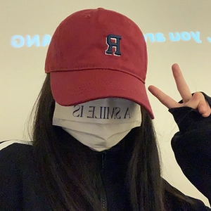 Close-up of a red baseball cap featuring a blue embroidered R letter on the front crown