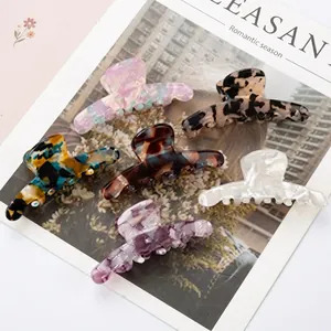 Assorted 9cm PVC hair claws in marble, leopard, and pearl finishes on fashion magazine
