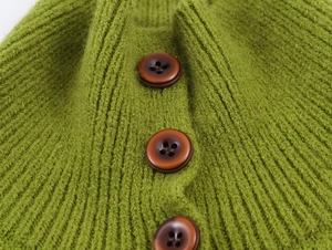 Detailed macro shot of green chunky knit cardigan featuring dark brown resin buttons