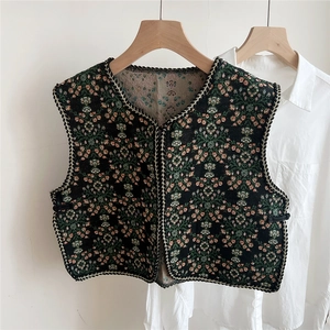 Detail of ethnic embroidered floral vest with V-neck lace-up and woven trim
