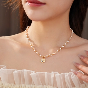Detail of pearl necklace with a gold celestial pendant featuring moon and star motifs
