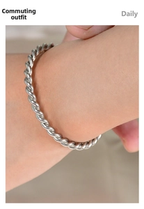 Macro shot of silver twisted rope texture cuff bracelet worn on female wrist for daily style