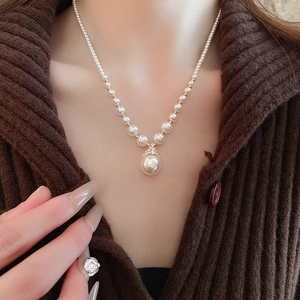 Détail d'un collier de perles rondes avec pendentif goutte sur le cou d'un mannequin