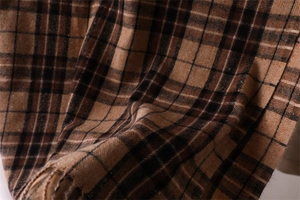 Close-up of brown plaid scarf texture showing soft cashmere-like fabric and fringe details
