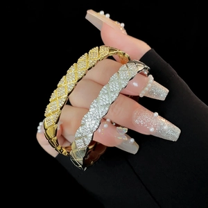 Close-up of gold and silver quilted zircon bracelets on hand with black background