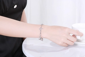 Detail of silver OT toggle bracelet with heartbeat lifeline design on female wrist