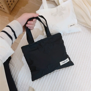 Detail of jacquard texture and bow embroidery on minimalist canvas mini tote bag