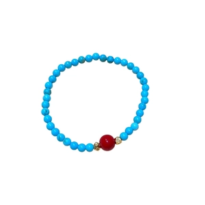 Bracelet en perles de turquoise avec perle d'agate rouge et espaceurs dorés sur fond blanc