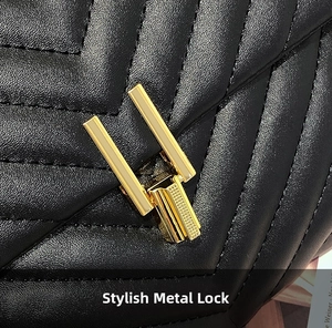 Close-up of golden rectangular lock and V-shaped quilted leather on black shoulder bag