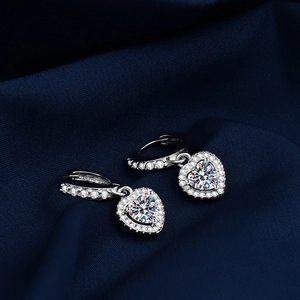Elegant silver heart earrings with moissanite drop on a luxurious blue silk backdrop