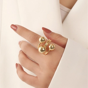 Detail of minimalist gold layered wrap ring with polished metal spheres on model's hand