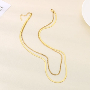 Double-layered gold stainless steel irregular chain necklace on beige textured background
