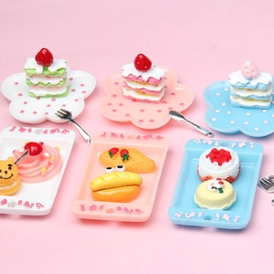 Miniature dollhouse dessert set with colorful resin cakes and polka dot plates on pink backdrop