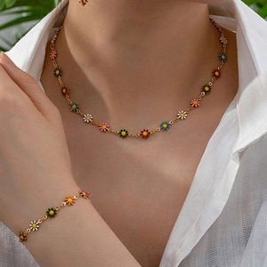 Detail of gold necklace and bracelet set with colorful daisy charms on a female model