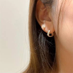 Gros plan d'une boucle d'oreille incurvée en argent 925 et d'une perle élégante