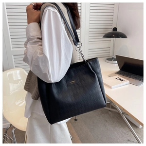 Detail of black quilted tote bag showing fine leather texture and metal strap rings