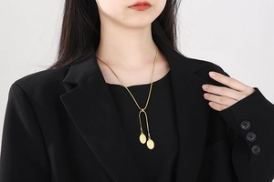 Close-up of golden snake chain necklace with double oval cameo coin pendants on model