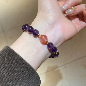 Detail of amethyst beaded bracelet featuring a single pink accent bead and gold floral spacers