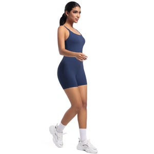 Side view of woman in navy blue strappy yoga bodysuit and white sneakers for fitness