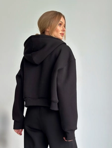 Vue arrière d'un sweat à capuche noir court et oversize avec poignets côtelés sur fond gris