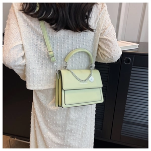Detail of light green PU leather bag featuring silver chain strap and brand lettering