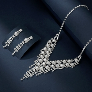 Detailed view of silver necklace and earrings set with white pearls and rhinestones