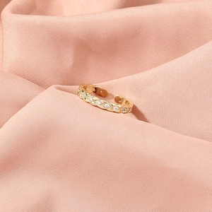 Detail of gold-plated twisted band ring with pavé-set cubic zirconia on pink satin
