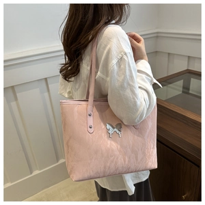 Pink tote bag detail showing unique pleated texture and silver butterfly buckle feature