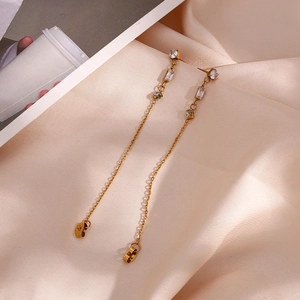 Macro detail of gold tassel drop earrings with clear cubic zirconia on champagne silk