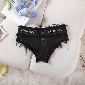 Dettaglio di pantaloncini di jeans neri con bordi sfilacciati e decorazioni di strass