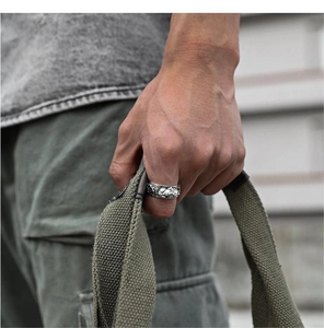 Close-up of men's vintage silver Pixiu ring worn on hand with industrial style outfit