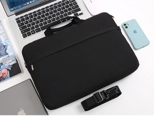 Top view of black laptop bag with shoulder strap and handles on a professional office desk