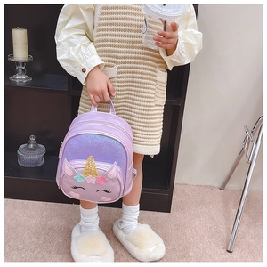 Detail of purple unicorn backpack with golden glitter horn and sparkly star decorations