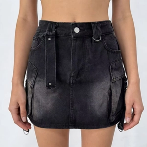 Dettaglio di gonna cargo in denim nero lavato con tasche utility e trama invecchiata