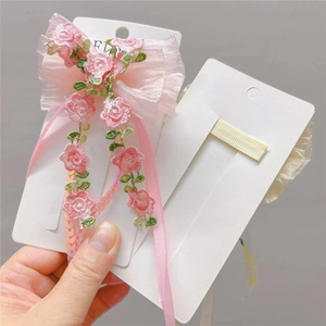 Detail of pink embroidered rose bow hair clip with sheer gauze and long ribbon